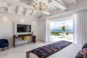 Un dormitorio con una cama y un televisor y un balcón. en Villa Fleurs de Lys, en Orient Bay