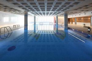 una grande piscina coperta con pavimentazione blu e una piscina di Elysia Park Luxury Apartment a Paphos Altre 15 foto