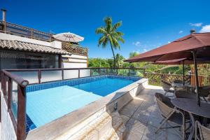 a swimming pool with a table and an umbrella at Moderno 1 Quarto Dentro da Vila in Praia do Forte
