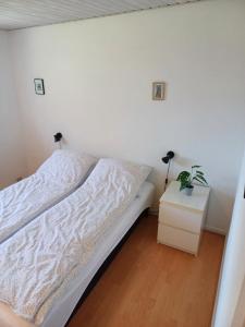 BjergbyBjergby Sønderbo feriehus的一间白色卧室,配有床和床头柜