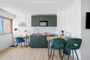 a kitchen with green cabinets and a table and chairs at Cosy & Chill Appartements - Superbe vue mer, Wifi & Clim in Cagnes-sur-Mer +39 photos