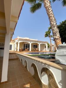 an exterior view of a house with a swimming pool and palm trees at Oasis Golf Villa in Caleta De Fuste