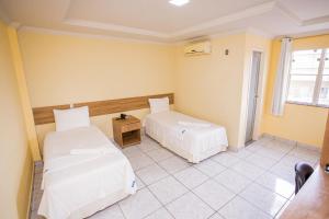 Barra do CordaHotel Diniz的一间卧室，有两张床、一张桌子和一扇窗户