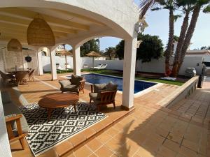 a patio with chairs and a table next to a pool at Oasis Golf Villa in Caleta De Fuste