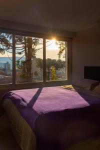 a bedroom with a large window and a bed with purple sheets at Barrancas de Nieva B03 in San Salvador de Jujuy