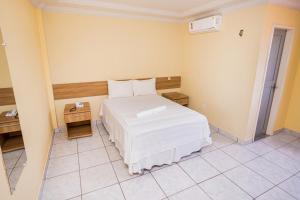 Barra do CordaHotel Diniz的卧室配有白色的床和床头柜。