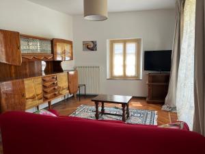 ein Wohnzimmer mit einem roten Sofa und einem Tisch in der Unterkunft Ca' Devalle in Bossolasco