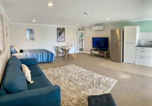 a living room with a blue couch and a kitchen at Churchill Oasis by the sea in Tauranga