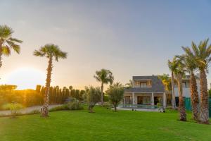 a house with palm trees in front of a yard at Villa vue atlas marrakech in Marrakech