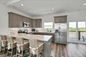 een keuken met een groot eiland met barkrukken bij Beachside Bliss by Sea Scape Properties in North Topsail Beach