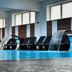 a pool with chairs and a water fountain at Hotel Pilot in Cazin