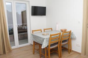 a dining room with a table with chairs and a television at Apartmani Mary S2 in Kukljica
