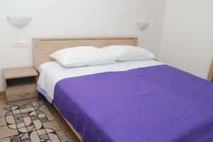 a bed with a purple blanket and two pillows at Apartmani Mary S2 in Kukljica