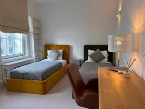 a bedroom with two beds and a table and a chair at Charming 3 Bed Luxury Flat in Central London in London