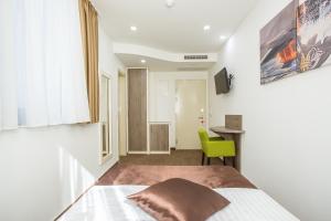 a bedroom with a bed and a green chair at Hotel National in Zagreb