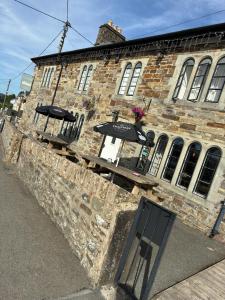 an old brick building with two umbrellas on it at Cross Hands Hotel in Llanybyther