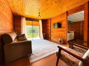 a living room with a couch and a large window at Sítio Raizes da Videira - SRR004 in Pinheiral