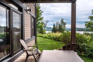 a table and chairs on a porch with a view of the water at Lakefront Mountain View - Resort Studio in Lac-Superieur