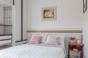 Schlafzimmer mit einem Bett mit rosa und weißen Kissen in der Unterkunft Suite Casal Mar e Lua em casa compartilhada in Ubatuba