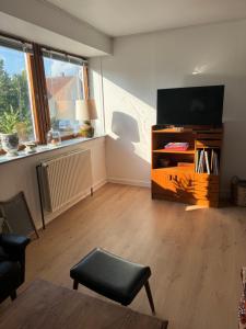 a living room with a flat screen tv and a chair at Lejlighed - med mulighed for Fitness in Nakskov