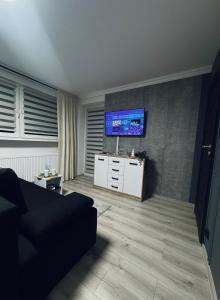 a living room with a couch and a tv on the wall at Marzecz HOME Lębork Centrum in Lębork +10 photos