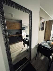 a mirror in a living room with a table and a kitchen at Marzecz HOME Lębork Centrum in Lębork