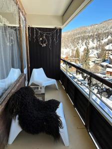 ein schwarzer Hund, der auf einem Balkon liegt und auf den Schnee hinausblickt in der Unterkunft Résidence Les Ecrins 1 - RESIDENCE LES ECRINS 1 MAE-0421 in Vars