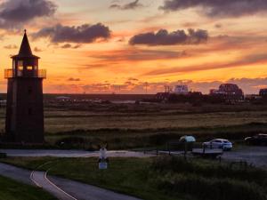 a person walking down a road near a lighthouse at Appartement Pension Feist in Dagebüll