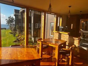 two wooden tables and chairs on a screened in porch at Hotel Faros del Sur in Ancud