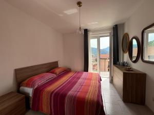 ein Schlafzimmer mit einem Bett und einem großen Fenster in der Unterkunft Sormano Apartments - THE V Collection in Sormano