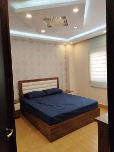 a bedroom with a bed with blue sheets and a ceiling at شقة مفروشة Furnished apartment in 6th Of October +6 photos