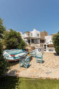 un patio con 2 sedie, un tavolo e una barca di Magnificent Mykonos Apartment Apartment Nexus 2 Bedrooms Private Terrace With Jacuzzi Outdoor Dining Area & Bbq Kalafatis a Kalafatis