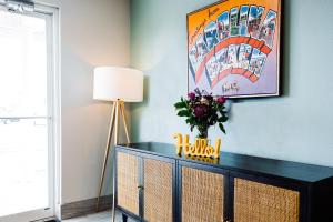 a black dresser with a vase of flowers and a lamp at The Windstar Hotel - Carolina Beach in Carolina Beach