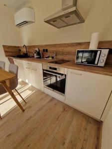 Una cocina con gabinetes blancos y un microondas y una mesa. en superbe logement privatif à côté de la via Rhona, en Charmes-sur-Rhône