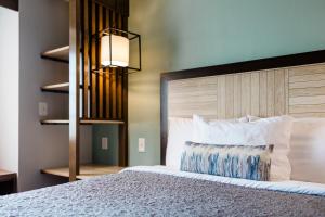 a bedroom with a large bed and a lamp at The Windstar Hotel - Carolina Beach in Carolina Beach