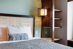 a bedroom with a bed with a pillow and a lamp at The Windstar Hotel - Carolina Beach in Carolina Beach