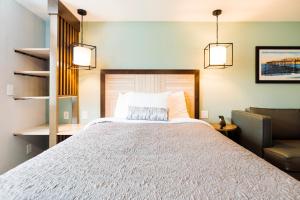 a bedroom with a large bed and a chair at The Windstar Hotel - Carolina Beach in Carolina Beach