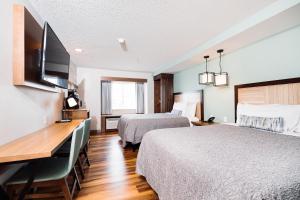 a hotel room with two beds and a desk at The Windstar Hotel - Carolina Beach in Carolina Beach