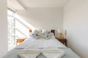 a bedroom with a bed with white sheets and a window at Harbor View Two Bedroom Apartment At Pinnacle in Wellington