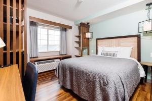 a bedroom with a bed and a desk and a window at The Windstar Hotel - Carolina Beach in Carolina Beach