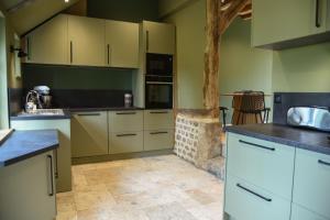 a kitchen with green walls and white cabinets at Le Cottage -Gîte de charme- in Boudeville