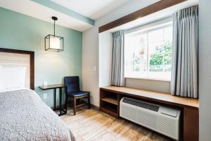 a bedroom with a bed and a window and a desk at The Windstar Hotel - Carolina Beach in Carolina Beach