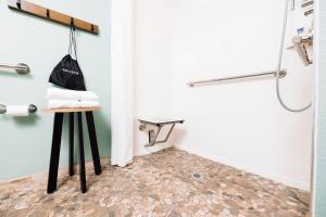 a bathroom with a shower and a towel on a stool at The Windstar Hotel - Carolina Beach in Carolina Beach