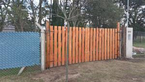 a wooden fence in a yard with a blue roof at CAMPING DON EMILIO in Lobos