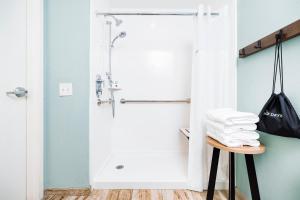 a bathroom with a shower and a stool with towels at The Windstar Hotel - Carolina Beach in Carolina Beach