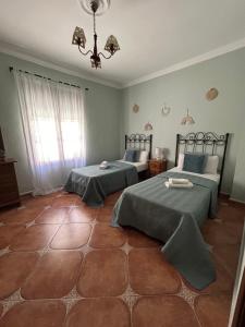 a bedroom with two beds and a chandelier at CASA RURAL EL CHAPARRO in Antequera +9 photos
