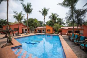 a large swimming pool with chairs and palm trees at Refúgio Da Ilha in Rio do Ouro