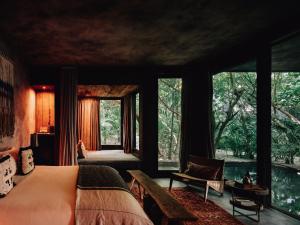 a bedroom with a bed and a large window at Nomade Tulum in Tulum