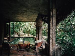 a room with a table and chairs and a pool at Nomade Tulum in Tulum
