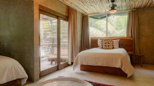 a bedroom with a bed and a large window at Nomade Tulum in Tulum +37 photos